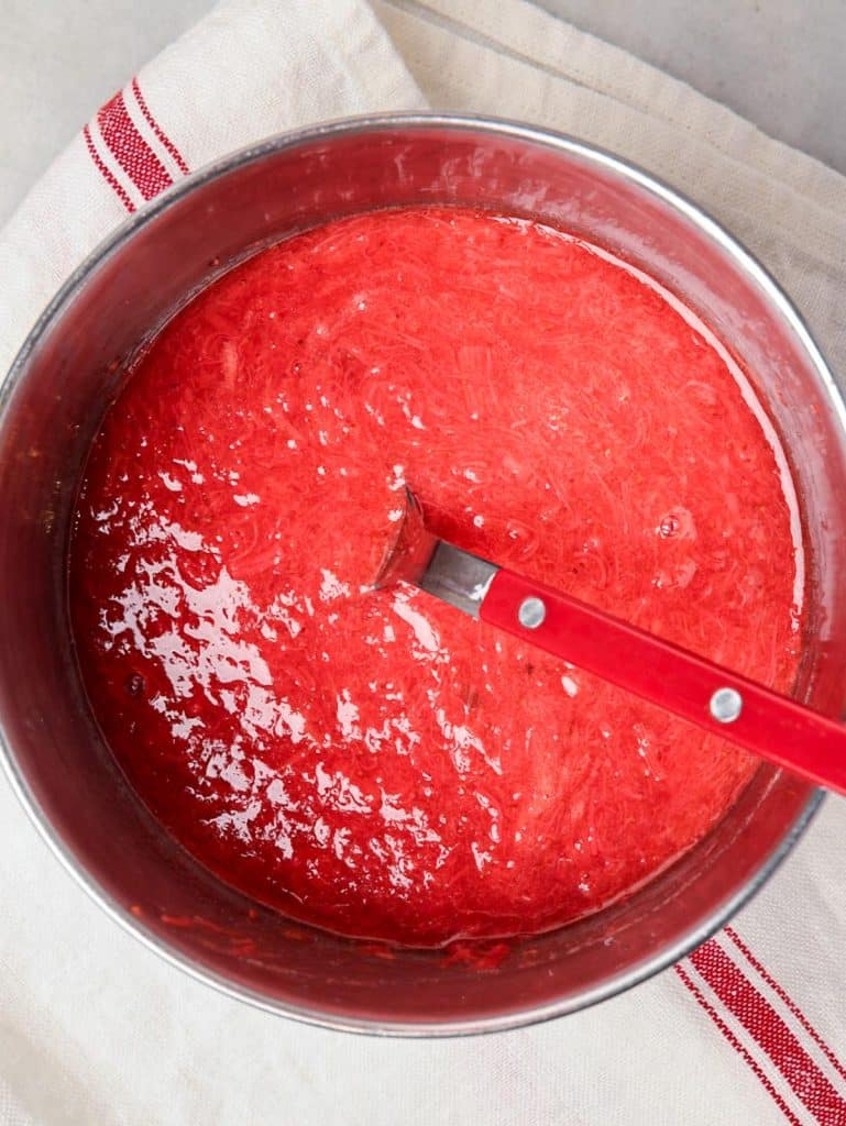 Homemade strawberry rhubarb jam cooked down in a saucepan