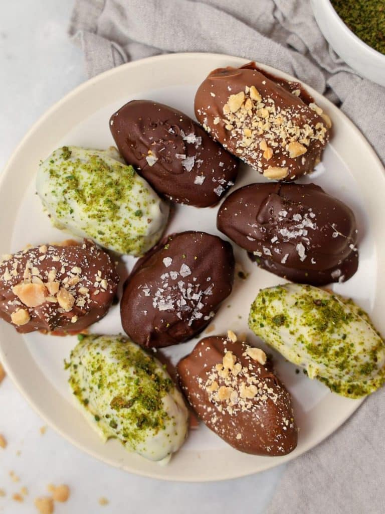 Stuffed dates dipped in dark, milk, and white chocolate on a white plate