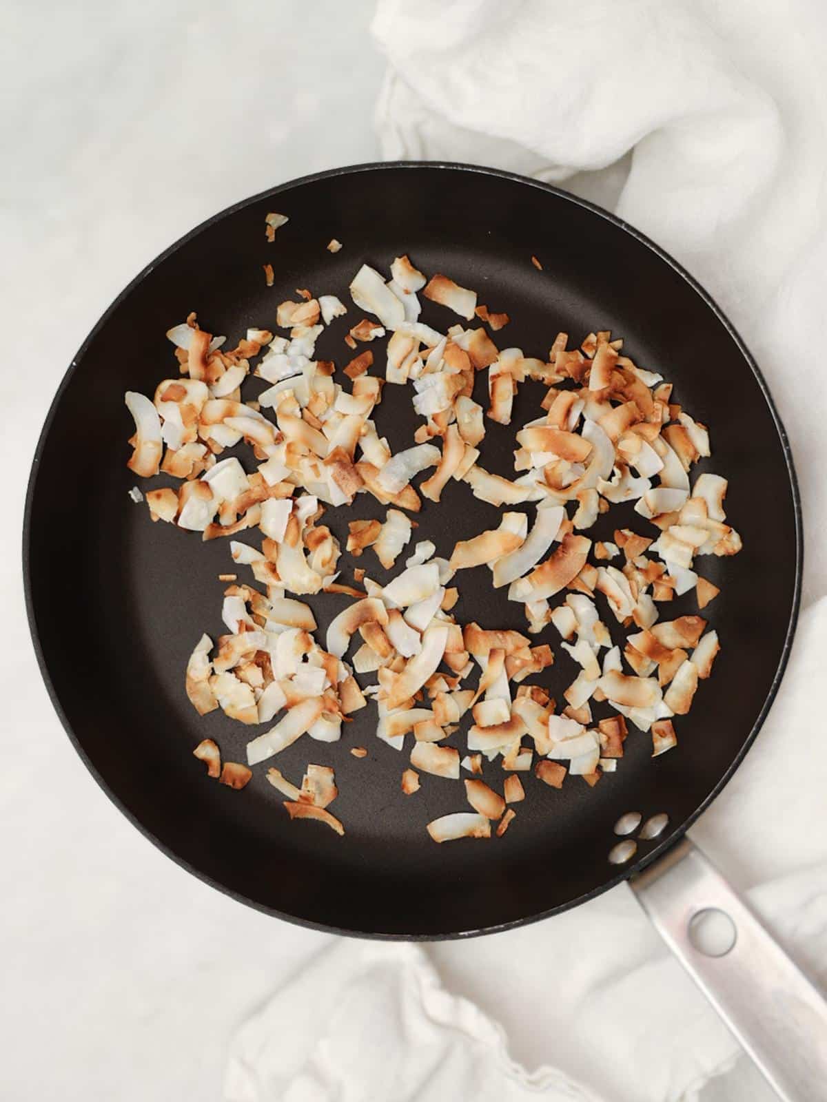 Golden toasted coconut flakes in a dry skillet