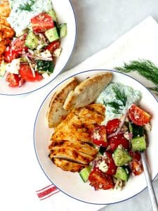Two greek chicken tzatziki bowls served side by side with fresh dill