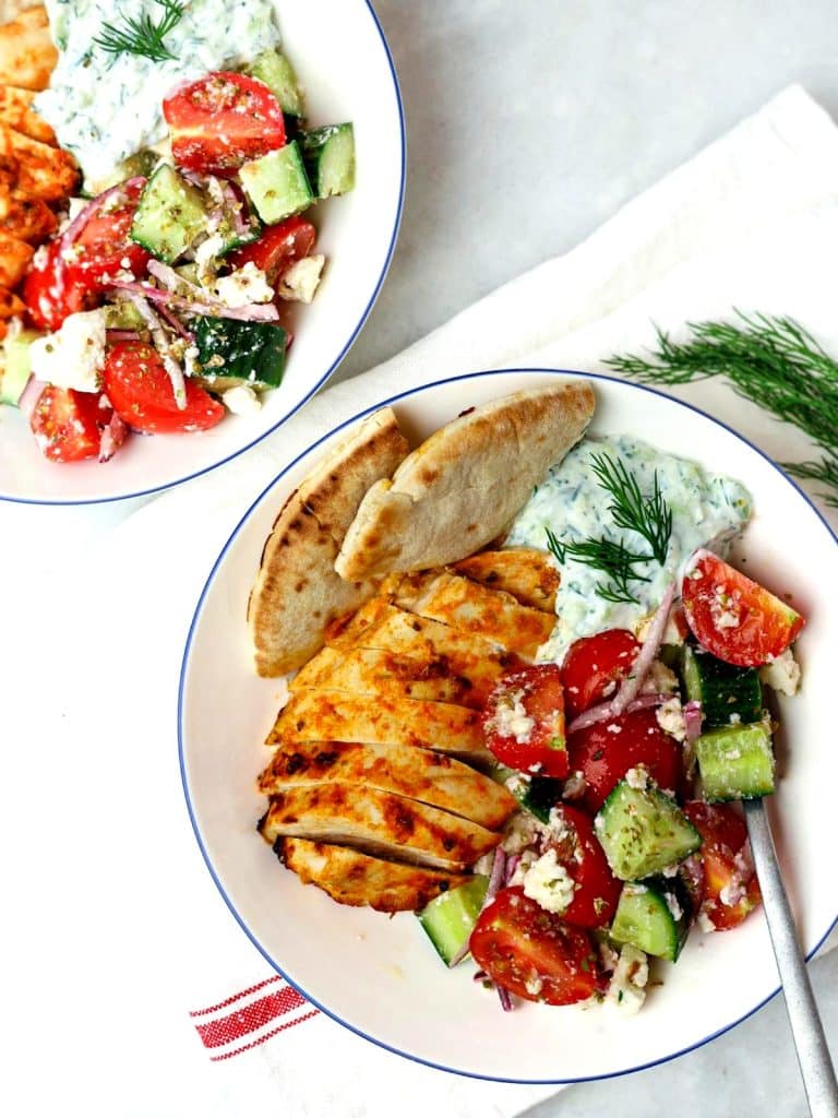Two greek chicken tzatziki bowls served side by side with fresh dill