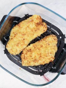 Two crispy panko-crusted chicken katsu cutlets in an air fryer basket after cooking