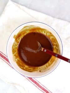Homemade tonkatsu sauce whisked together in a small white bowl with a red spoon