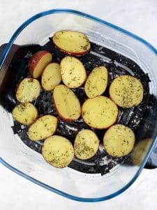 Halved baby potatoes seasoned with garlic powder and rosemary in a clear air fryer basket