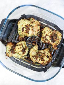Pesto-marinated chicken thighs cooked golden in an air fryer basket