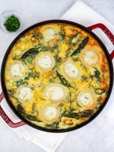 Golden baked asparagus frittata with goats cheese rounds and dill on top