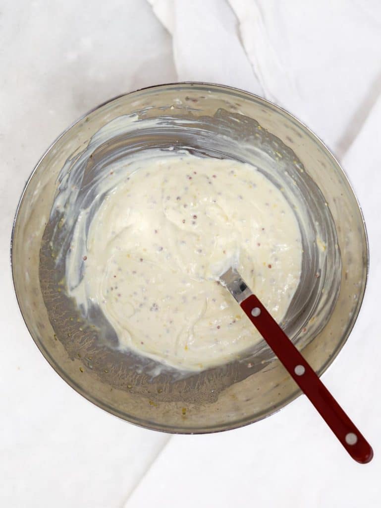 Creamy greek yogurt dressing whisked smooth with mustard seeds visible throughout