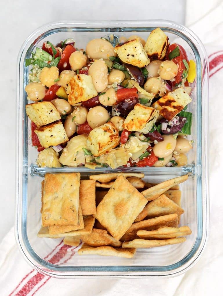 Chickpea dense bean salad in a glass meal prep container with pita crackers