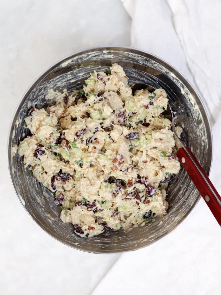 Cranberry almond chicken salad mixed in a stainless bowl with shreddy chicken and creamy dressing