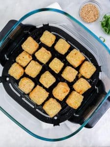 Golden crispy tofu cubes in the air fryer basket after cooking
