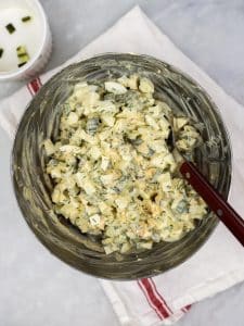Spicy dill pickle egg salad mixed together in a glass bowl flecked with fresh dill