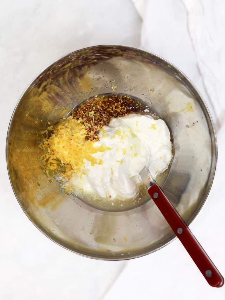 Greek yogurt, Dijon, whole-grain mustard, and lemon zest in a stainless bowl for chicken salad dressing