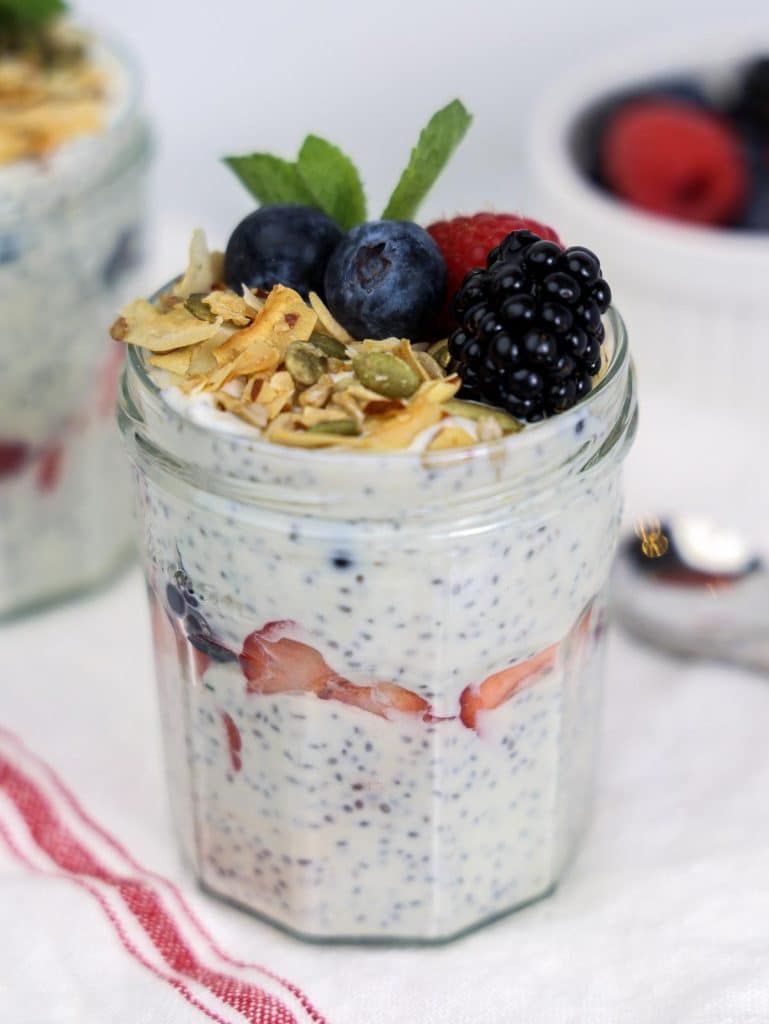 Greek yogurt with chia seeds and berries layered in a jar with toasted coconut, blueberry, raspberry, and blackberry topping