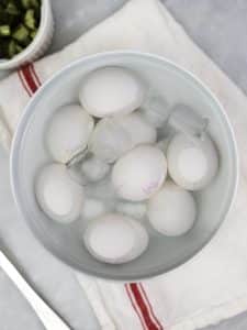 Hard-boiled eggs cooling in an ice water bath for spicy dill pickle egg salad