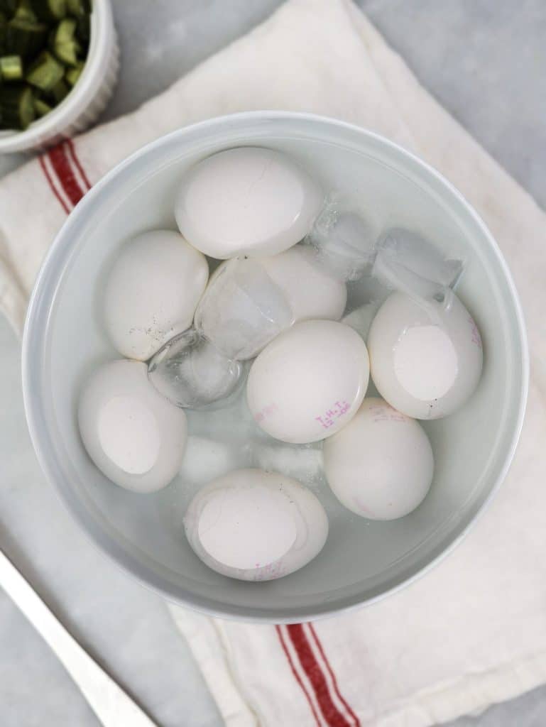 Hard-boiled eggs cooling in an ice water bath for spicy dill pickle egg salad