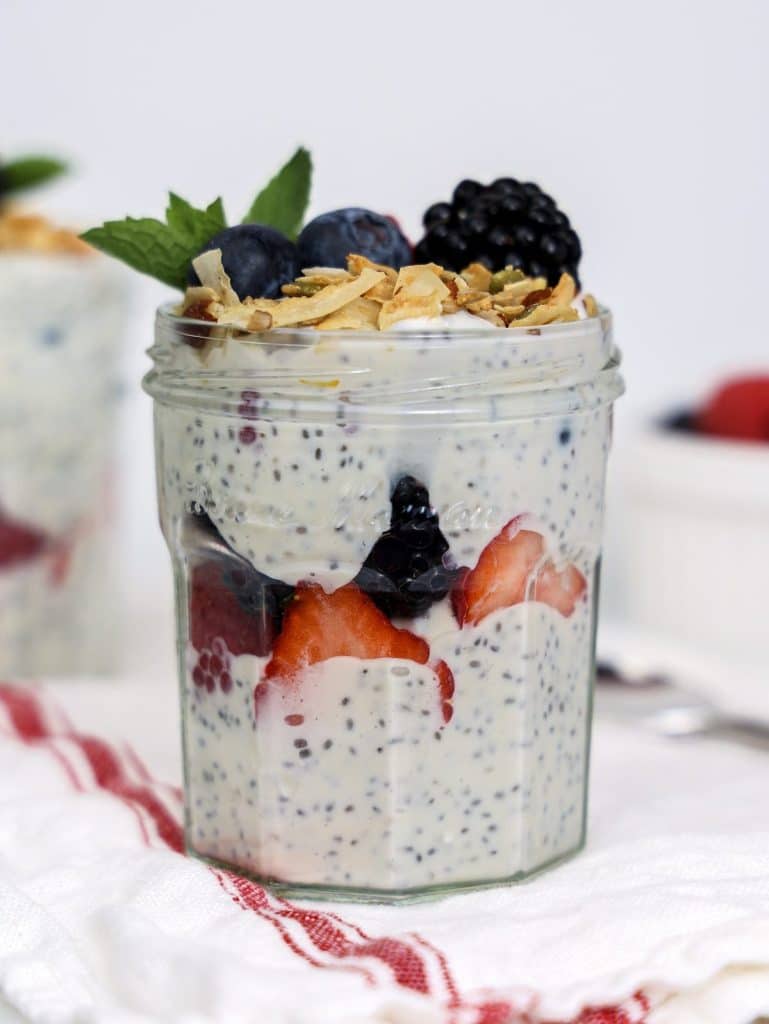 High-protein chia seed yogurt parfait layered with strawberries and blackberries in a glass jar topped with mint