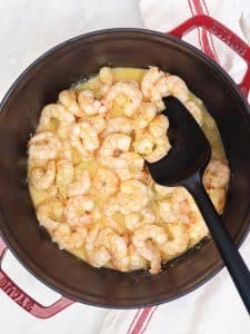Lemon garlic butter shrimp searing in a deep red pot