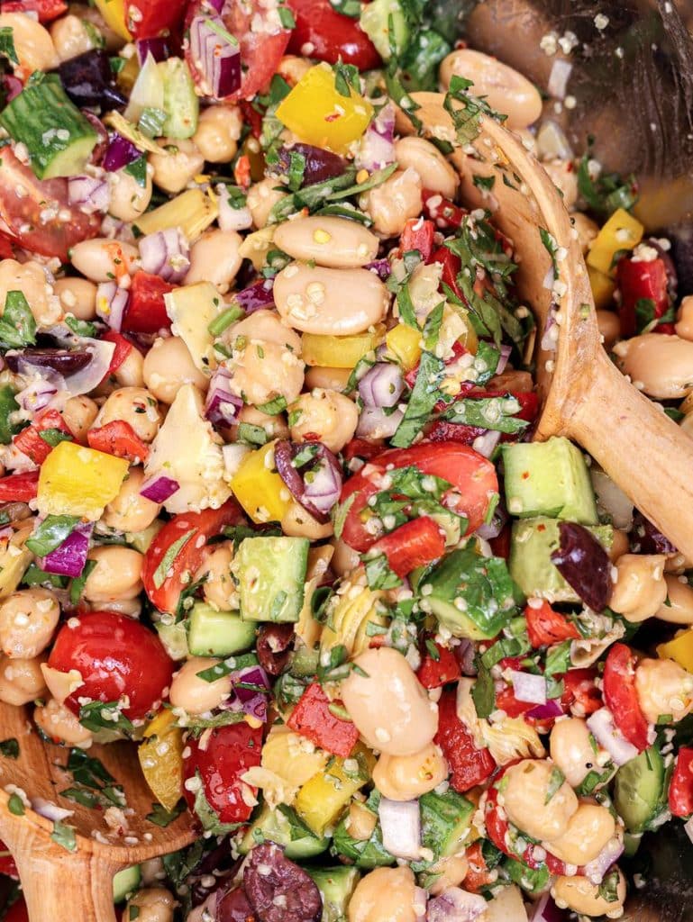 Close-up of dressed Mediterranean dense bean salad with cucumbers, peppers, beans, and herbs