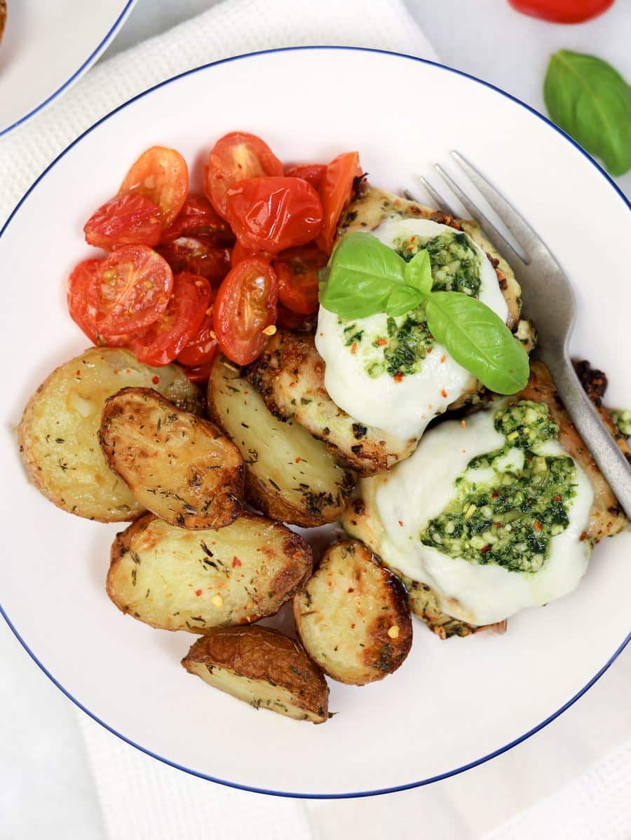 Pesto chicken recipe made in the air fryer with crispy baby potatoes and burst cherry tomatoes