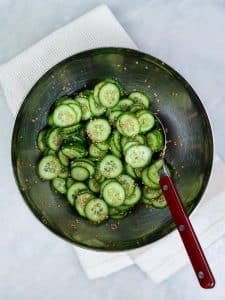 Quick pickled cucumber coins tossed with sesame seeds in a metal bowl