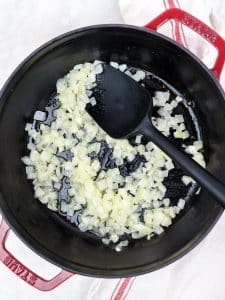 Diced yellow onion sautéing in a pot for shrimp orzo