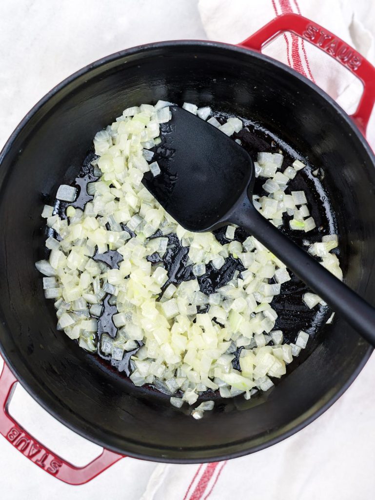 Diced yellow onion sautéing in a pot for shrimp orzo