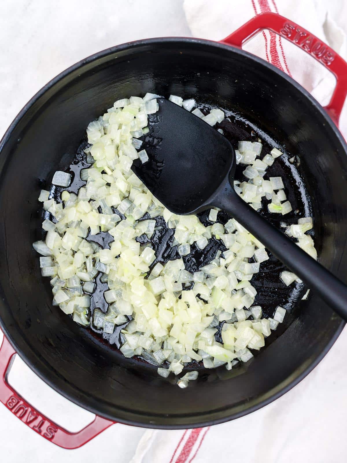 Diced yellow onion sautéing in a pot for shrimp orzo