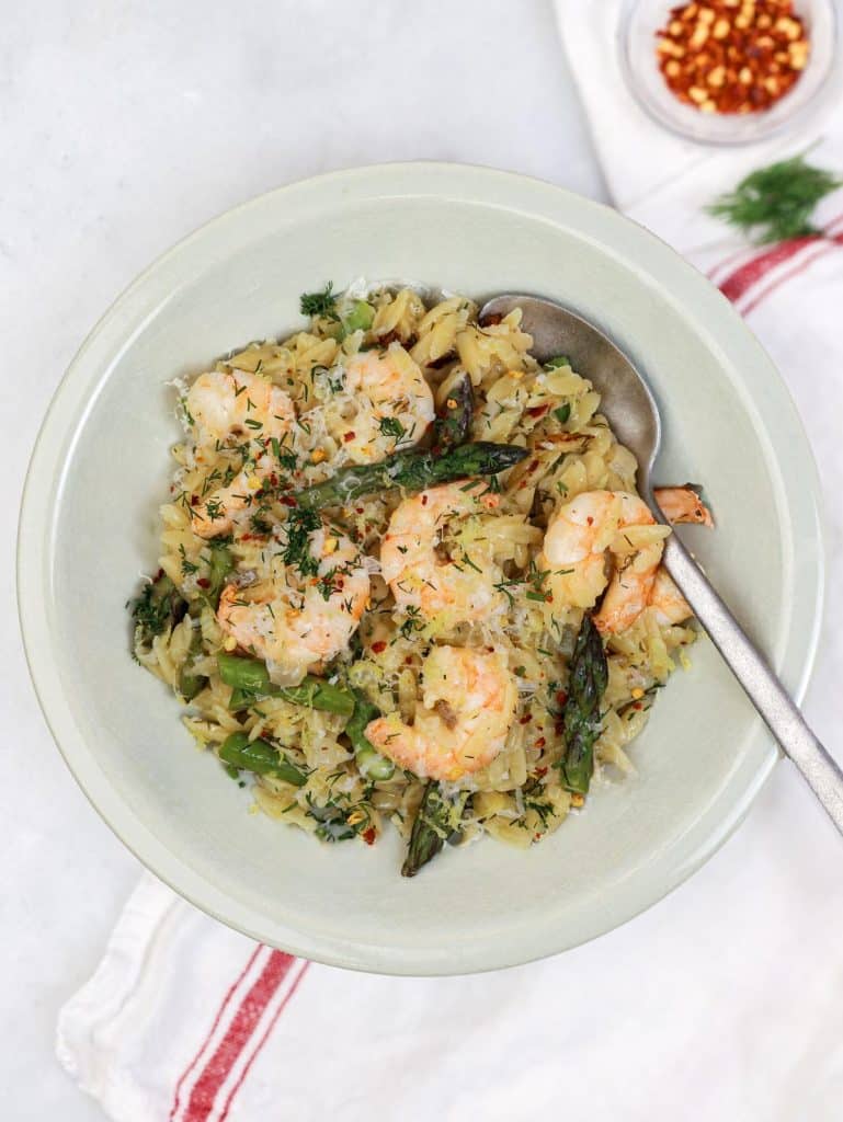 Shrimp and asparagus orzo with lemon, fresh dill, and parmesan in a green bowl