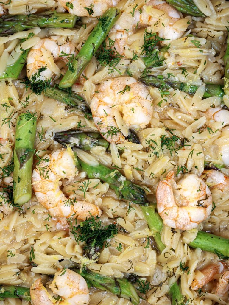 Close up of shrimp orzo with asparagus, fresh dill, and parmesan
