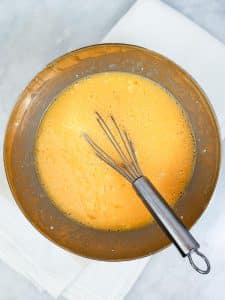 Whisked eggs and cottage cheese in a metal bowl ready for spring frittata recipe