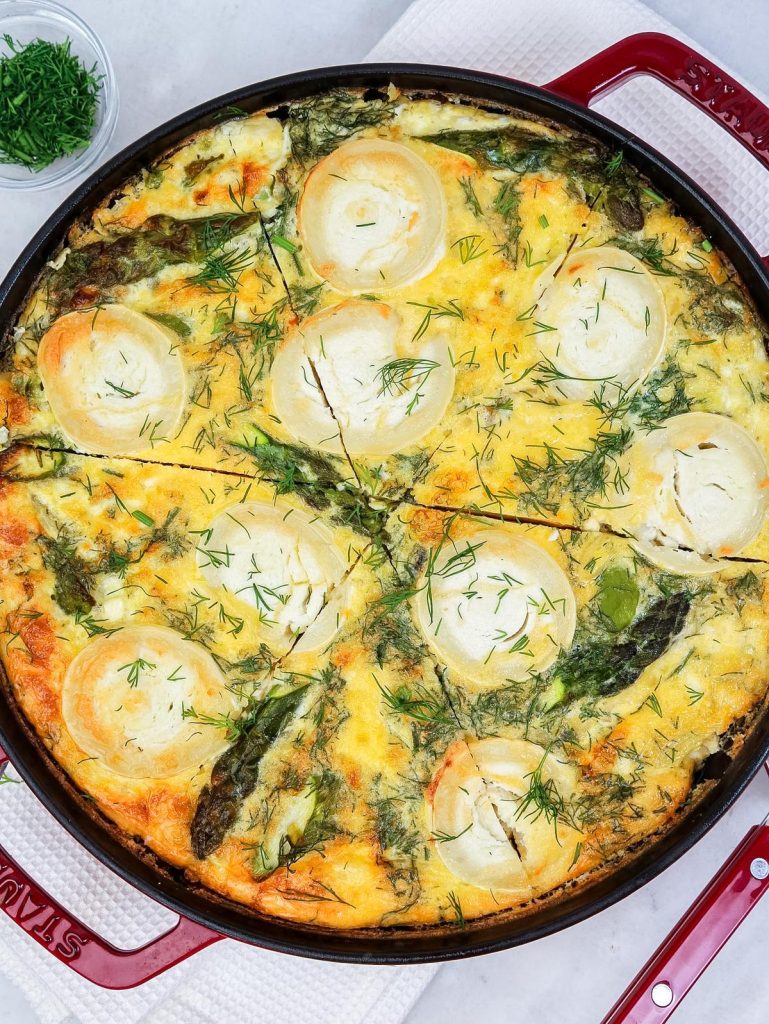 Spring frittata sliced into wedges in a red Staub skillet