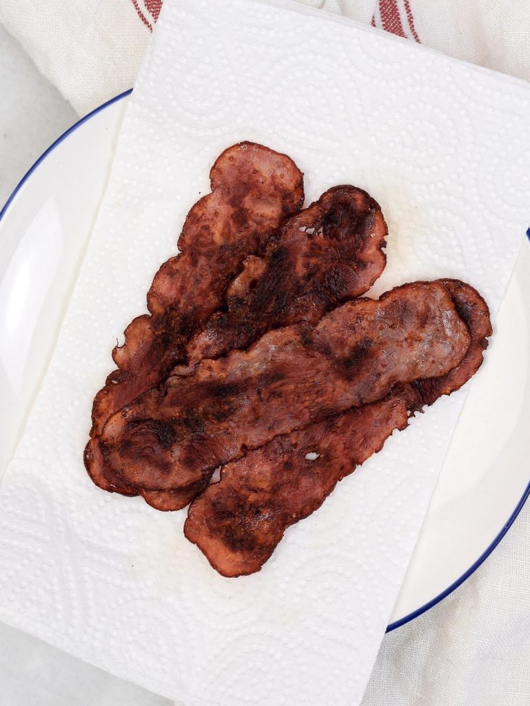 Crispy turkey bacon on a paper-towel-lined plate, draining before being added to high-protein breakfast tacos