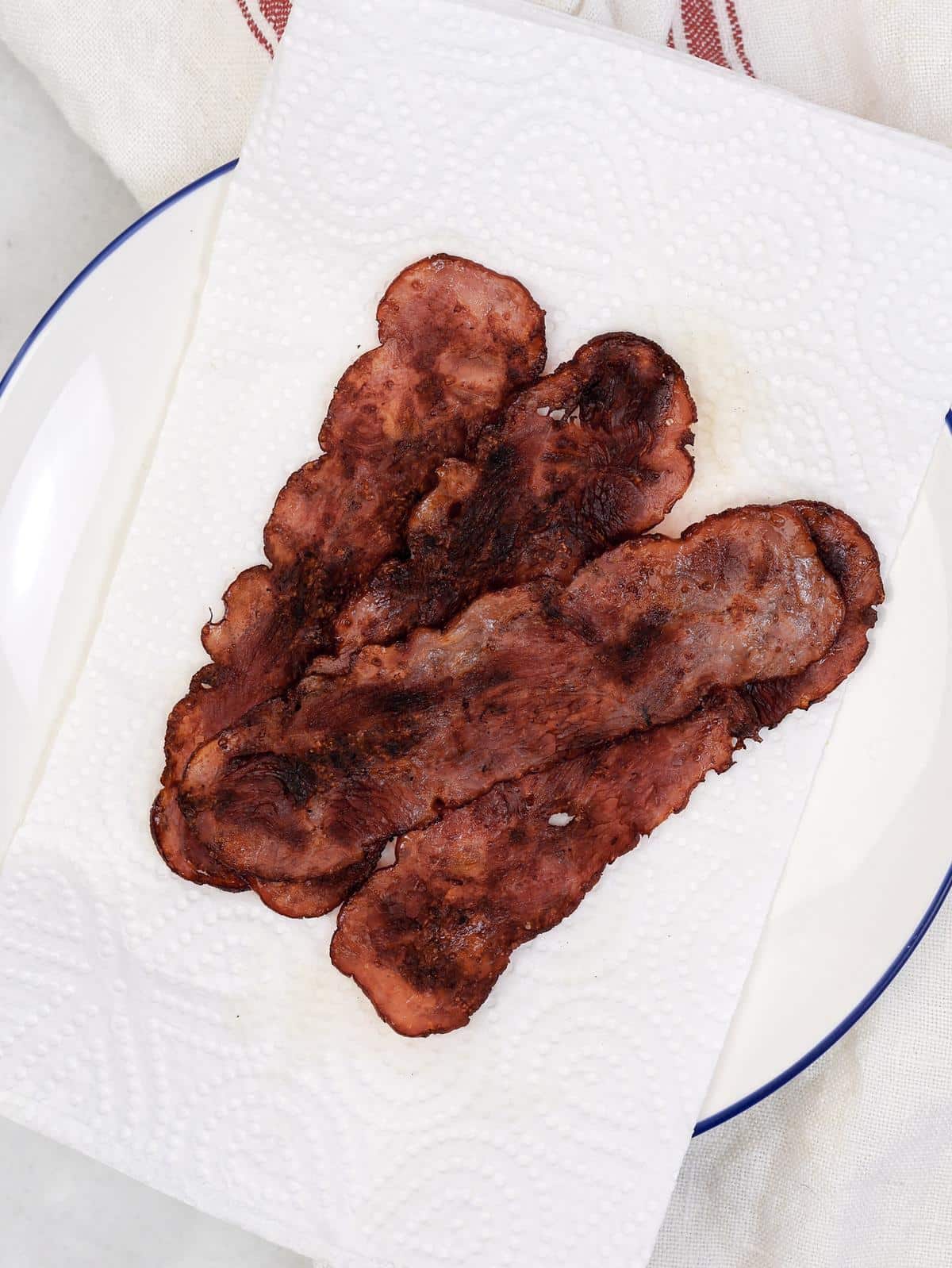 Crispy turkey bacon on a paper-towel-lined plate, draining before being added to high-protein breakfast tacos