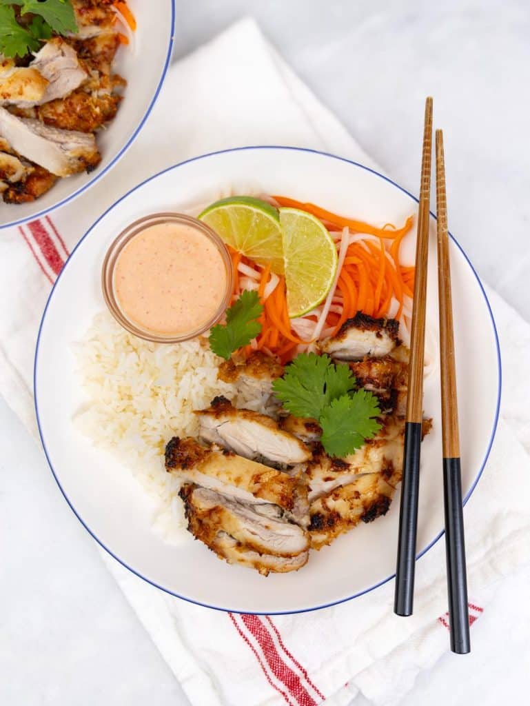 Air fryer lemongrass chicken banh mi bowl with rice, pickled vegetables, sriracha mayo, and chopsticks