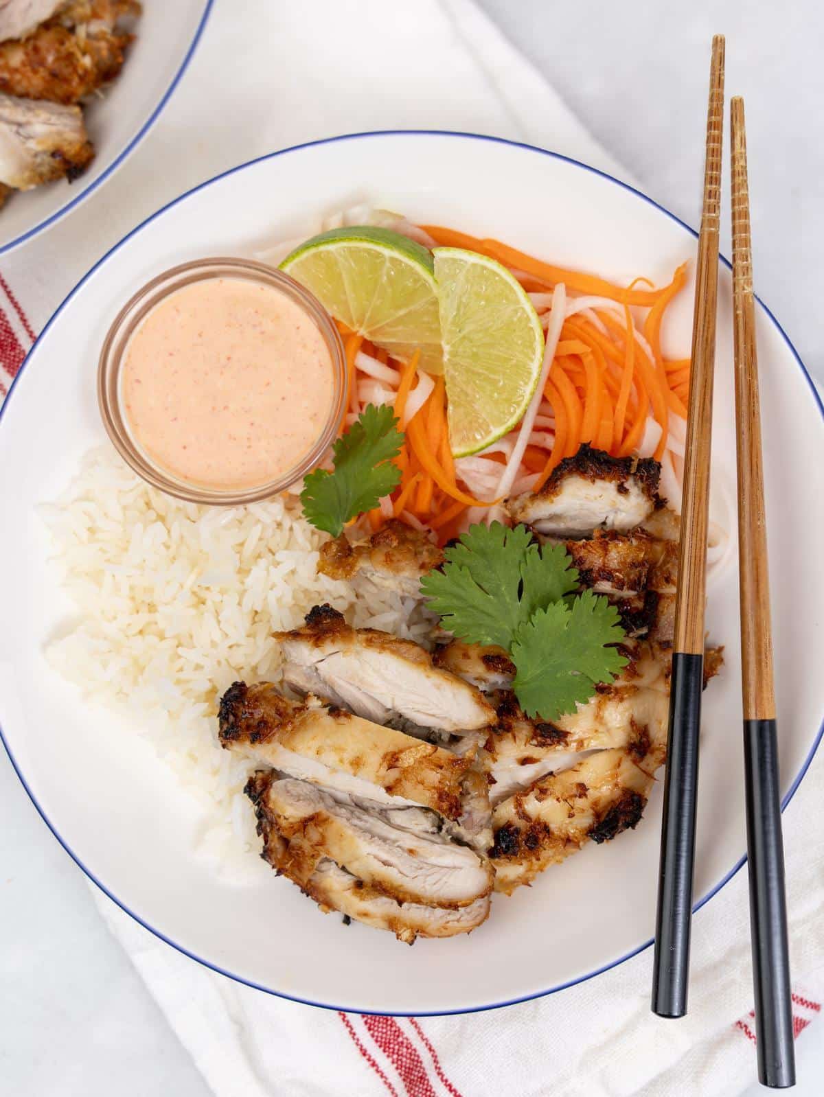 Air fryer lemongrass chicken sliced over jasmine rice with pickled carrot and daikon, sriracha mayo, and lime