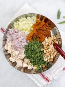 Diced chicken, shallot, celery, dried apricots, herbs, and cashews arranged in a bowl