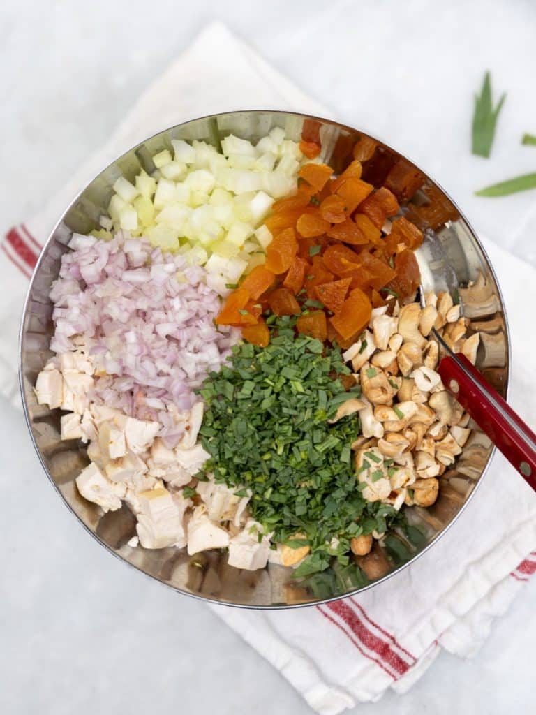 Diced chicken, shallot, celery, dried apricots, herbs, and cashews arranged in a bowl