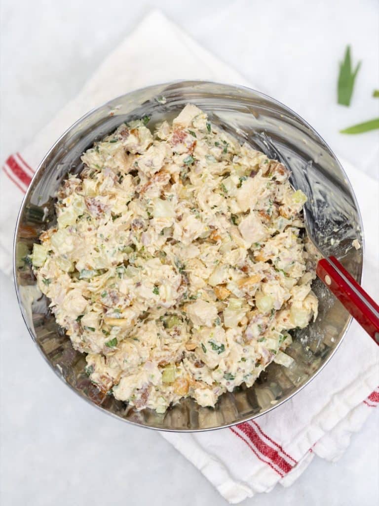 Apricot chicken salad freshly mixed in a metal bowl with a red-handled spoon