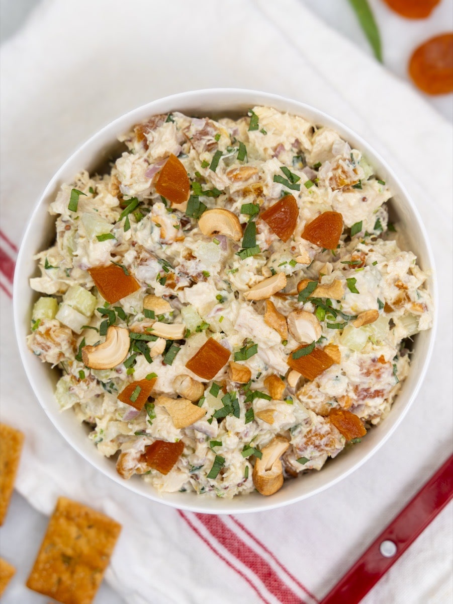 Apricot chicken salad with toasted cashews and fresh herbs in a white bowl