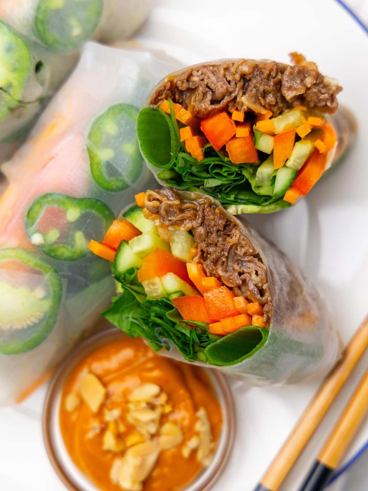 Close-up of beef summer rolls cut in half showing beef, carrot, cucumber, and bell pepper inside