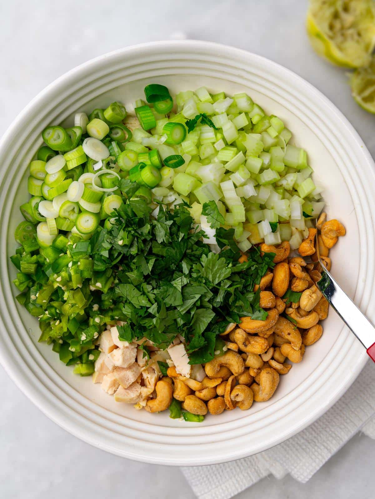 Chicken, celery, green onion, jalapeño, cilantro, and cashews in a bowl before mixing