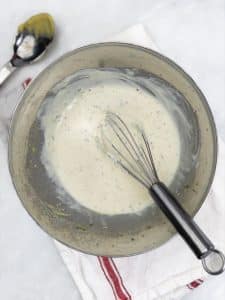 Whisked greek yogurt and mustard dressing in a metal bowl