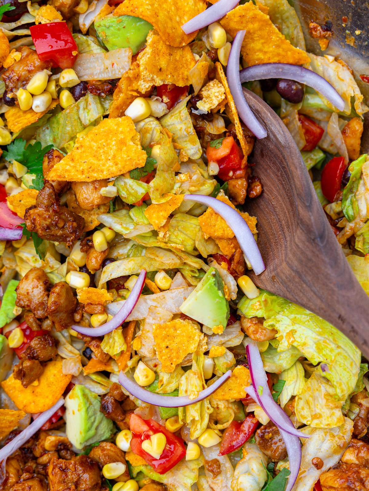 Close-up of tossed taco salad with iceberg lettuce, tortilla chips, red onion and corn