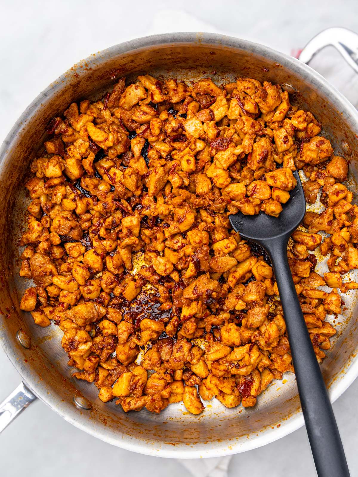 Crispy diced chipotle chicken cooking in a stainless steel skillet
