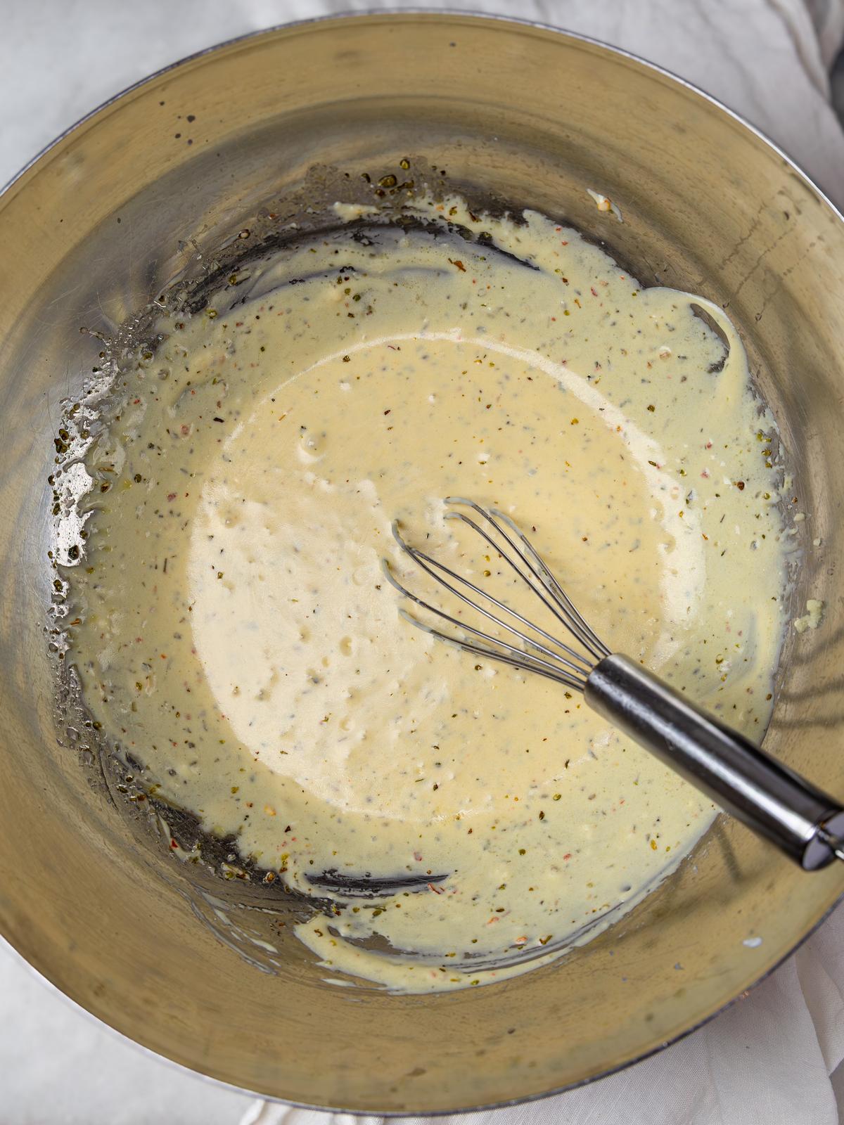 Whisked creamy greek yogurt grinder dressing in a metal mixing bowl