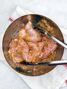 Boneless chicken thighs coated in Vietnamese lemongrass marinade in a metal mixing bowl