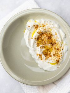Greek yogurt swooshed on a plate and topped with za'atar and olive oil