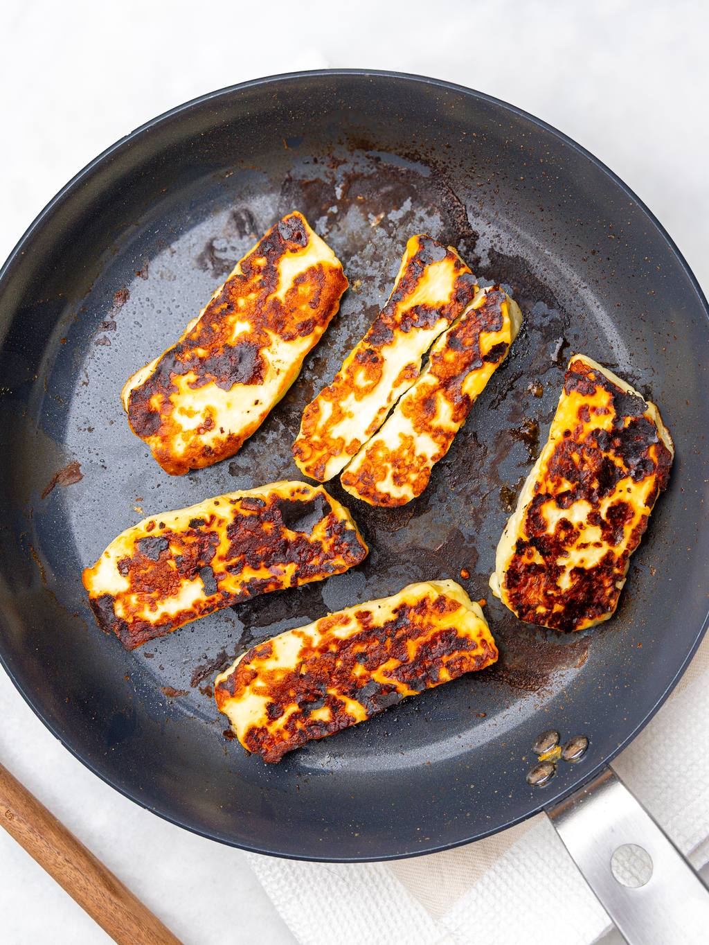 Pan-fried halloumi slices browned and crisp in a skillet