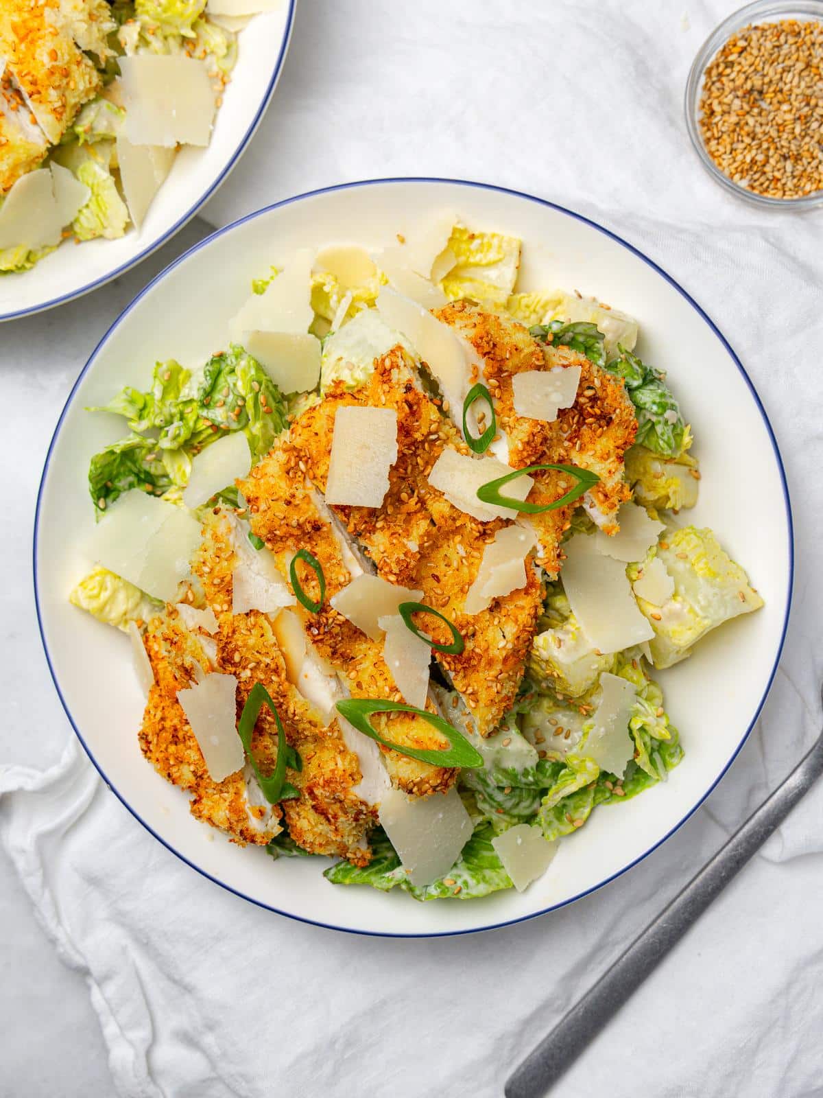 Overhead view of miso caesar salad with crispy chicken, parmesan and green onion