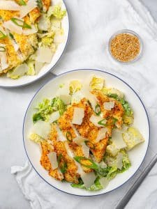 Two bowls of miso caesar salad with crispy sesame chicken and shaved parmesan